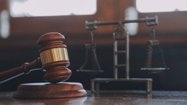 Hukuk bürosunun kütüphanesindeki hukuk kitapları ve adalet terazileri masanın üzerinde. Hukuk eğitimi kavramı.