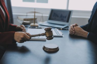 Adalet ve hukuk kavramı. Bir mahkeme salonunda tokmakla çalışan, bilgisayar ve kenetlenme klavyesi, gözlük takan bir erkek yargıç, sabah ışığında masada.