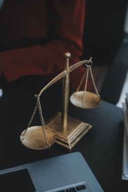 Adalet ve hukuk kavramı. Bir mahkeme salonunda tokmakla çalışan, bilgisayar ve kenetlenme klavyesi, gözlük takan bir erkek yargıç, sabah ışığında masada.