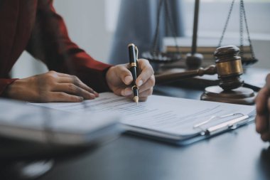 Adalet ve hukuk kavramı. Bir mahkeme salonunda tokmakla çalışan, bilgisayar ve kenetlenme klavyesi, gözlük takan bir erkek yargıç, sabah ışığında masada.