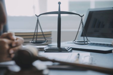 Adalet ve hukuk kavramı. Bir mahkeme salonunda tokmakla çalışan, bilgisayar ve kenetlenme klavyesi, gözlük takan bir erkek yargıç, sabah ışığında masada.