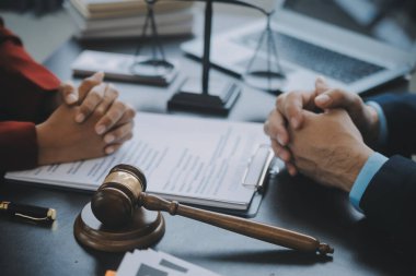 Adalet ve hukuk kavramı. Bir mahkeme salonunda tokmakla çalışan, bilgisayar ve kenetlenme klavyesi, gözlük takan bir erkek yargıç, sabah ışığında masada.