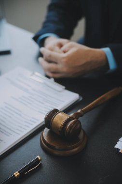 Adalet ve hukuk kavramı. Bir mahkeme salonunda tokmakla çalışan, bilgisayar ve kenetlenme klavyesi, gözlük takan bir erkek yargıç, sabah ışığında masada.