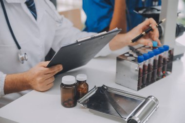 Tıbbi çalışan laboratuvar önlüğü ve steril maskesi arkasında çalışıyoruz onun meslektaşım süre mikroskop analiz yapıyor