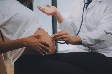 Kadın doktor hamile kadını steteskopla kontrol ediyor. Hamile bir kadın için bakım kavramı