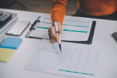 Asyalı iş kadını dizüstü bilgisayar kullanıyor ve ofiste hesap makinesi ile çalışıyor, mali raporu, iş planı yatırımını, mali analiz konseptini analiz etmeyi planlıyor..