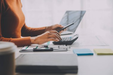 Asyalı iş kadını dizüstü bilgisayar kullanıyor ve ofiste hesap makinesi ile çalışıyor, mali raporu, iş planı yatırımını, mali analiz konseptini analiz etmeyi planlıyor..