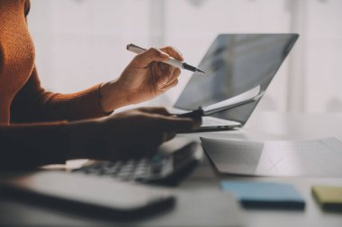 Asyalı iş kadını dizüstü bilgisayar kullanıyor ve ofiste hesap makinesi ile çalışıyor, mali raporu, iş planı yatırımını, mali analiz konseptini analiz etmeyi planlıyor..
