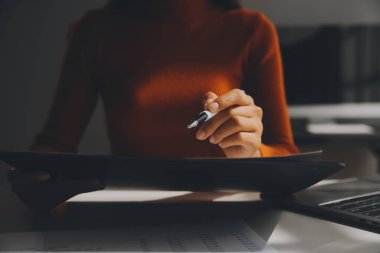 Asyalı iş kadını dizüstü bilgisayar kullanıyor ve ofiste hesap makinesi ile çalışıyor, mali raporu, iş planı yatırımını, mali analiz konseptini analiz etmeyi planlıyor..