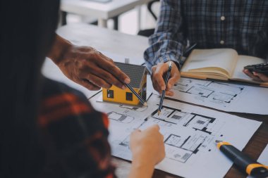 A team of construction engineers talks to managers and construction workers at the construction site. Quality inspection, work plan, home and industrial building design project