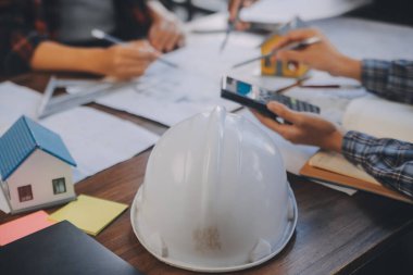 A team of construction engineers talks to managers and construction workers at the construction site. Quality inspection, work plan, home and industrial building design project