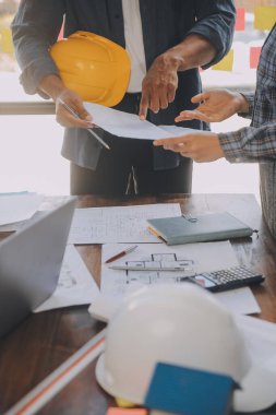 A team of construction engineers talks to managers and construction workers at the construction site. Quality inspection, work plan, home and industrial building design project