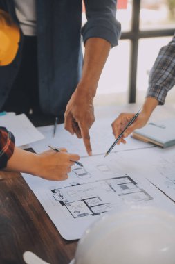 A team of construction engineers talks to managers and construction workers at the construction site. Quality inspection, work plan, home and industrial building design project