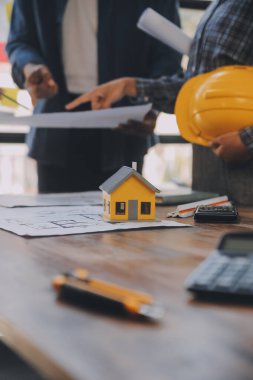 A team of construction engineers talks to managers and construction workers at the construction site. Quality inspection, work plan, home and industrial building design project