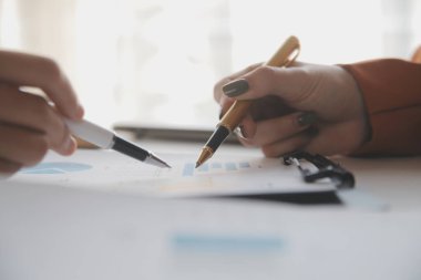 İş kadını eliyle grafiğe işaret ediyor ve bilgisayar ekranında liste yapmak için bir kalem kullanıyor