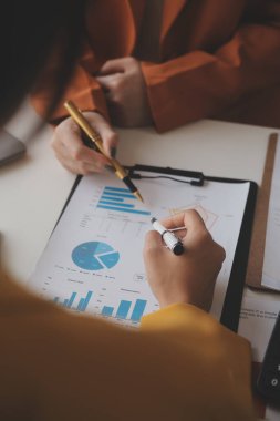 İş kadını eliyle grafiğe işaret ediyor ve bilgisayar ekranında liste yapmak için bir kalem kullanıyor