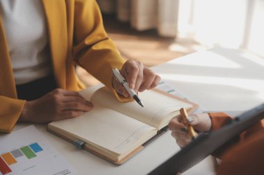 İş kadını eliyle grafiğe işaret ediyor ve bilgisayar ekranında liste yapmak için bir kalem kullanıyor