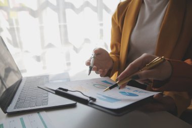 İş kadını eliyle grafiğe işaret ediyor ve bilgisayar ekranında liste yapmak için bir kalem kullanıyor