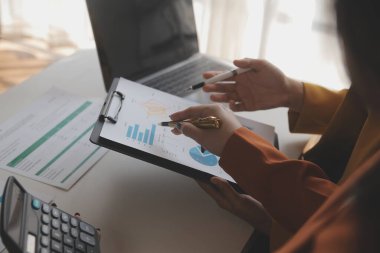 İş kadını eliyle grafiğe işaret ediyor ve bilgisayar ekranında liste yapmak için bir kalem kullanıyor
