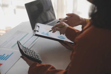 İş kadını eliyle grafiğe işaret ediyor ve bilgisayar ekranında liste yapmak için bir kalem kullanıyor
