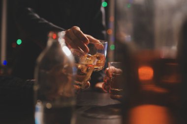 Kutlama gecesi, bardağa viski dök. Kutlamaya gelen arkadaşlarına ver.