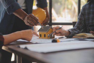 A team of construction engineers talks to managers and construction workers at the construction site. Quality inspection, work plan, home and industrial building design project