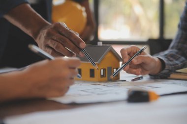 A team of construction engineers talks to managers and construction workers at the construction site. Quality inspection, work plan, home and industrial building design project