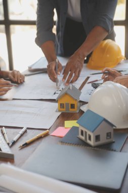 A team of construction engineers talks to managers and construction workers at the construction site. Quality inspection, work plan, home and industrial building design project