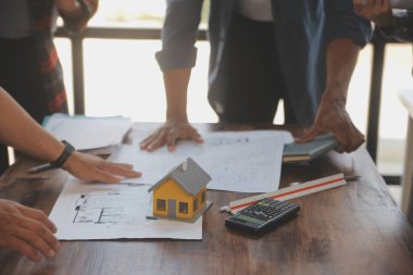 A team of construction engineers talks to managers and construction workers at the construction site. Quality inspection, work plan, home and industrial building design project