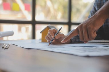 A team of construction engineers talks to managers and construction workers at the construction site. Quality inspection, work plan, home and industrial building design project