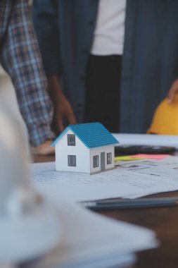 A team of construction engineers talks to managers and construction workers at the construction site. Quality inspection, work plan, home and industrial building design project