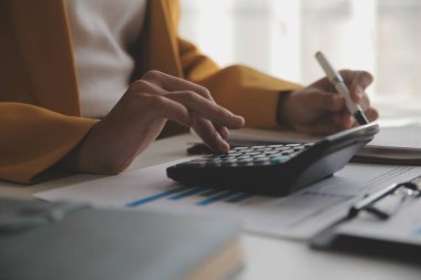 Vergi hesaplayan kadın, masada hesap makinesi kullanan.