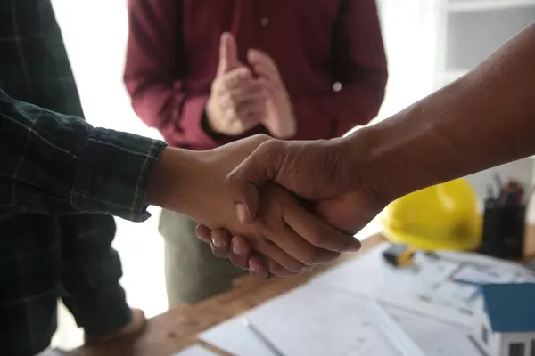 Engineer and contractor join hands after signing contract,They are having a modern building project together. successful cooperation team concept