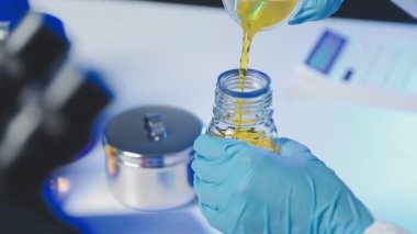 Bilim adamı elinde pipetle bir tüp tutuyor.
