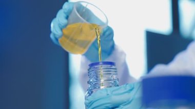 Bilim adamı şişede sıvı bir pipet tutuyor.