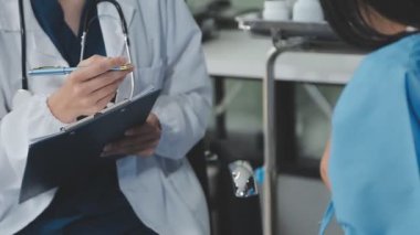 Kadın doktor, hastane koğuşunda dikilirken panoya bir şeyler yazıyor. Doktor hastaları üzerinde çalışıyor..