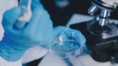 Bilim adamı elinde bir pipet tutuyor ve sıvıyı hazırlıyor.