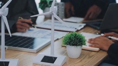 İş adamı, modern ofisteki ahşap masada rüzgar enerjisi santrali ile tablet kullanıyor..