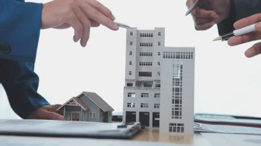 Masasında, binasında, ev modelinde bir modeli olan iş adamı ve iş kadını.