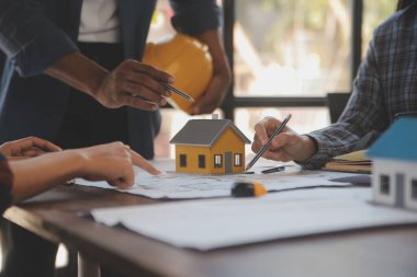 A team of construction engineers talks to managers and construction workers at the construction site. Quality inspection, work plan, home and industrial building design project