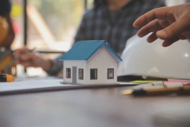 A team of construction engineers talks to managers and construction workers at the construction site. Quality inspection, work plan, home and industrial building design project