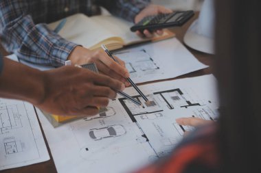 A team of construction engineers talks to managers and construction workers at the construction site. Quality inspection, work plan, home and industrial building design project
