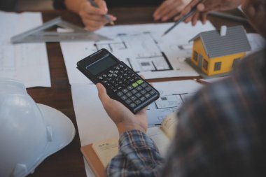 A team of construction engineers talks to managers and construction workers at the construction site. Quality inspection, work plan, home and industrial building design project