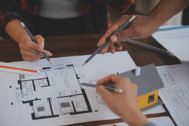 A team of construction engineers talks to managers and construction workers at the construction site. Quality inspection, work plan, home and industrial building design project