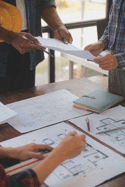 A team of construction engineers talks to managers and construction workers at the construction site. Quality inspection, work plan, home and industrial building design project