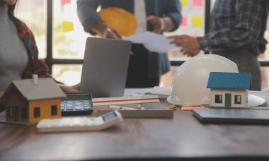 A team of construction engineers talks to managers and construction workers at the construction site. Quality inspection, work plan, home and industrial building design project