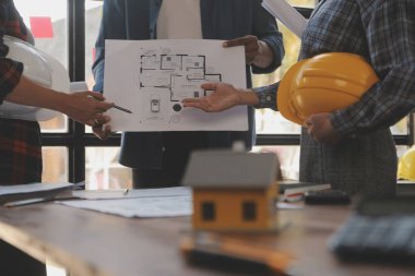 A team of construction engineers talks to managers and construction workers at the construction site. Quality inspection, work plan, home and industrial building design project