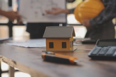 A team of construction engineers talks to managers and construction workers at the construction site. Quality inspection, work plan, home and industrial building design project