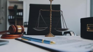 Adalet terazisi tokmak ve kitapla ofisteki ahşap masada.