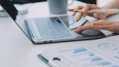İş kadınlarının elleri masadaki mali grafik ve grafikle dizüstü bilgisayarda yazarken.